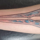A person with a tattoo based on an energy sword from Halo rests their arm on an armrest.